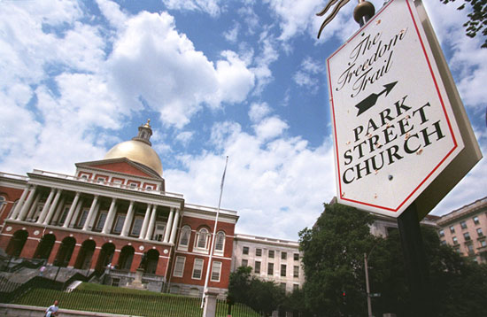 Image of a freedom trail sign pointing the way to Park Street Church in Boston, with the Massachusetts State House in the background